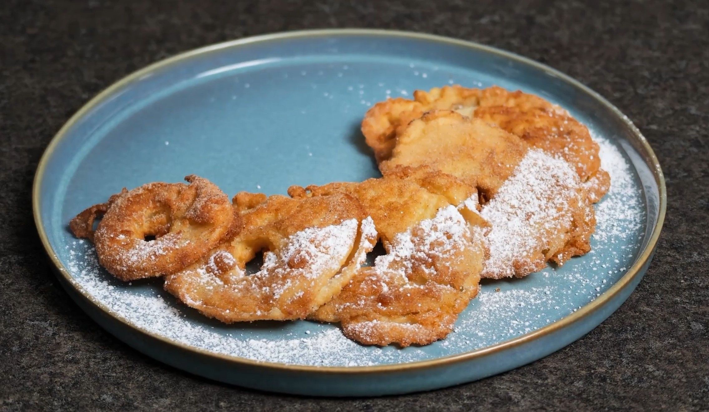 Apfelradln saupoudrés de sucre à glacer dans une assiette bleue